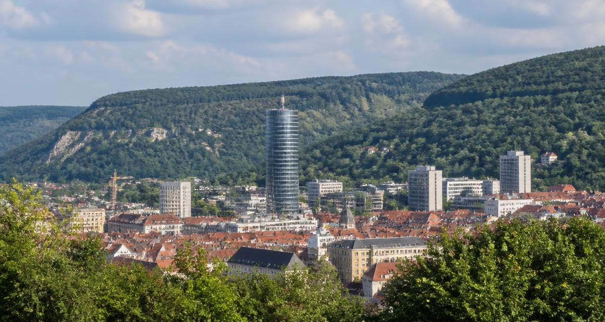 Stadtansicht von Jena mit dem JenTower und den bewaldeten Hängen des Saaletals
